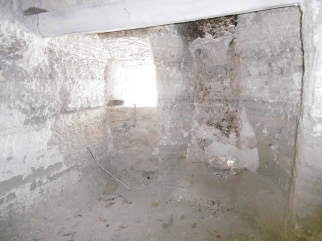 Interior view of a rustic cave house in Benamaurel, Granada, showcasing stone walls and natural ligh.