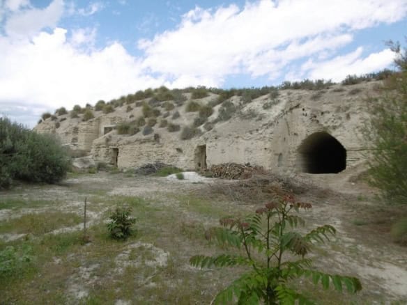 Cave house in Benamaurel, Granada, with natural rock formations and cave entrances.