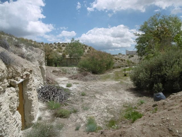 Cave house in Benamaurel, Granada, surrounded by natural landscape and rugged terrain.