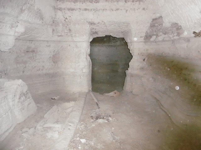 Interior view of a cave house in Benamaurel, Granada, showing rough stone walls and an opening to an.