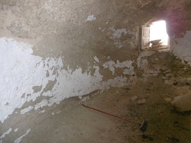 Cave house interior in Benamaurel, Granada, showing rustic stone walls and small window.
