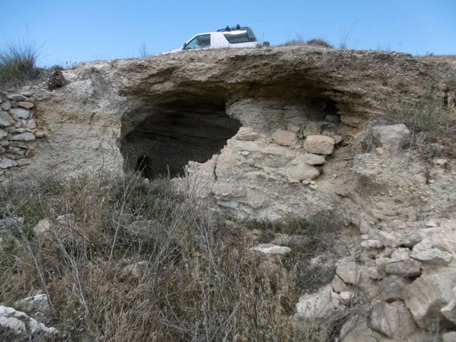 Cave house in Benamaurel, Granada, with a vehicle parked above the entrance.