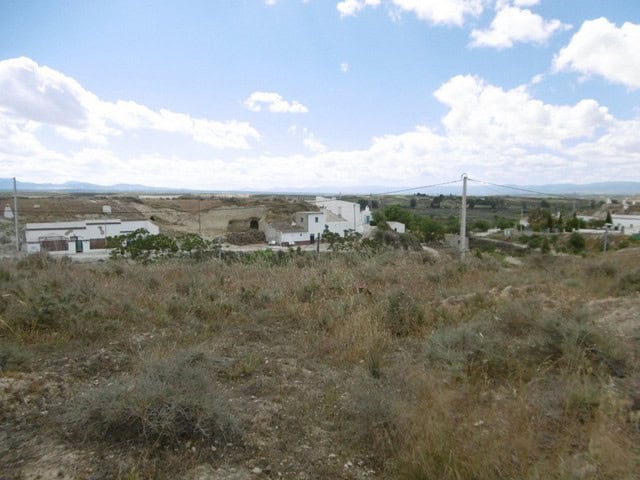 Cave house in Benamaurel, Granada with surrounding landscape and open sky.