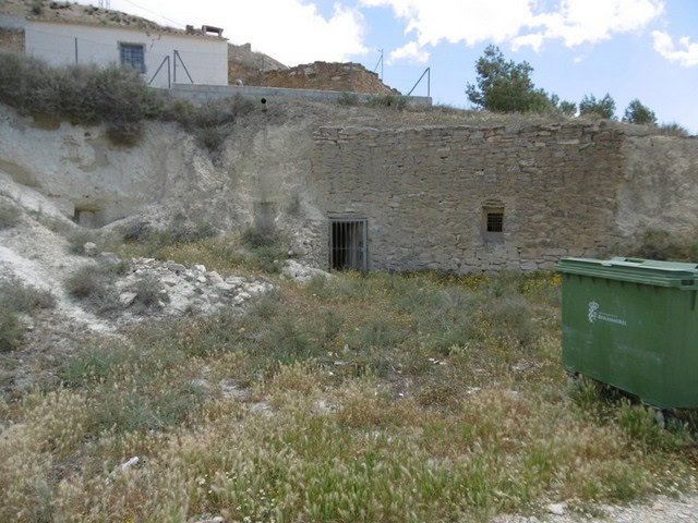 Cave house in Benamaurel, Granada, with rustic stone walls and surrounding natural landscape.