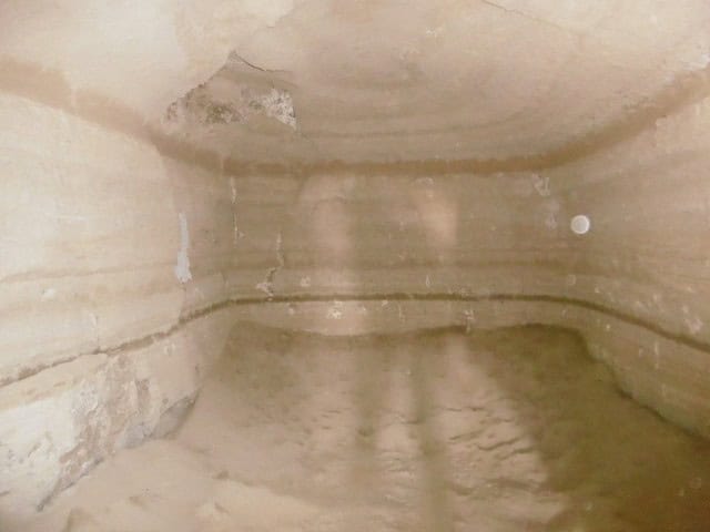 Interior of a cave house in Benamaurel, Granada, showing natural stone walls and earthy floor.