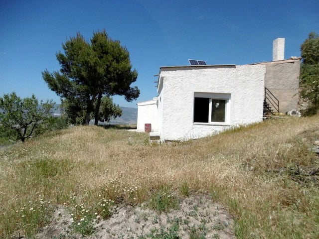 Rural property for sale in Sufli, Almeria, featuring a white house with solar panels and scenic coun.