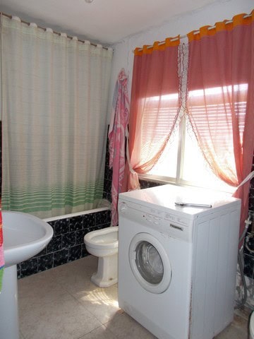 Interior of a small bathroom with washing machine, toilet, and sink in Seron, Almeria.