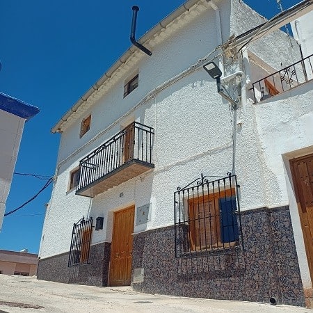 Charming village house in Hinojares, Jaen featuring white walls, wooden doors, and cozy balconies.