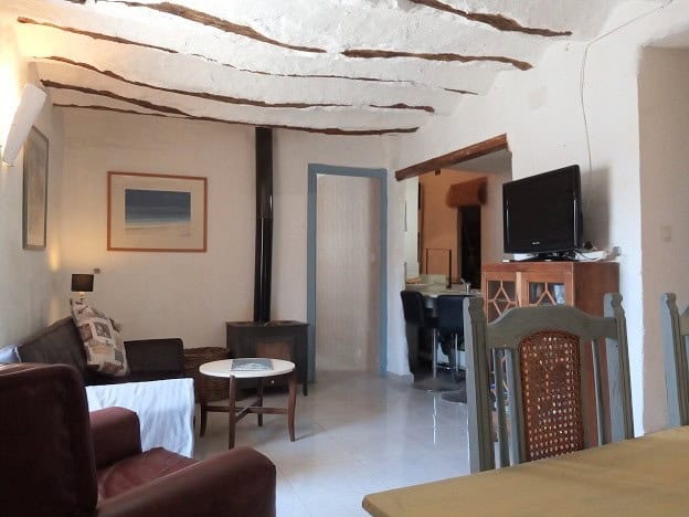 Cozy living room with rustic ceiling beams and modern amenities in Hinojares, Jaen.