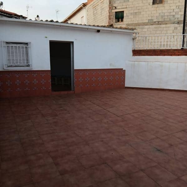 Terrace of a village house in Villanueva de las To, Granada, with tiled flooring and white walls.