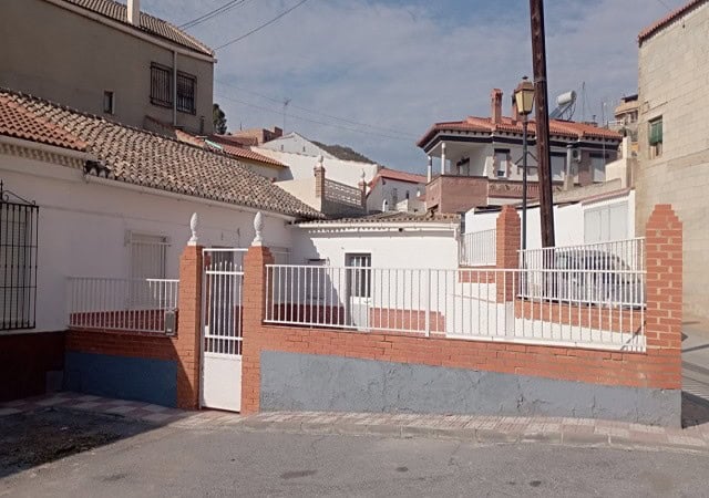 Charming village property with a white fence and brick accents in Villanueva de las To, Granada.