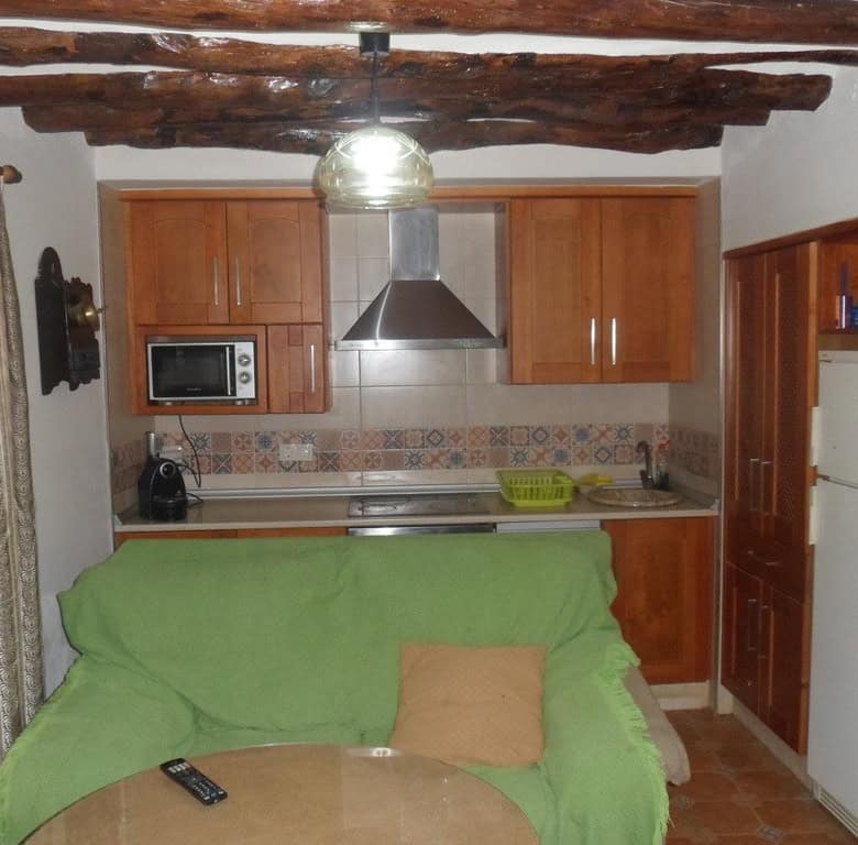 Charming village home in Cullar, Granada with a cozy kitchen and rustic wooden ceiling beams.