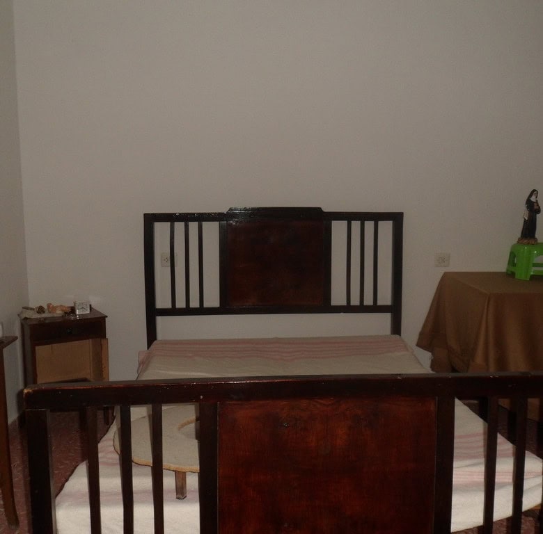 Charming village property in Cullar, Granada, featuring a simple bedroom with wooden furniture and b.