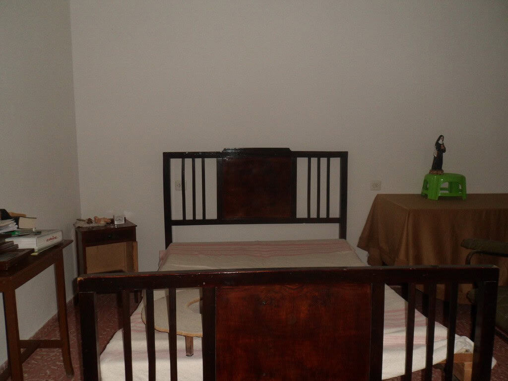 Charming village property in Cullar, Granada, featuring a simple bedroom with wooden furniture and b.