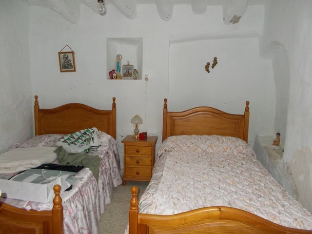 Charming bedroom with two wooden beds in a rustic Bayarque home, featuring whitewashed walls and vin.