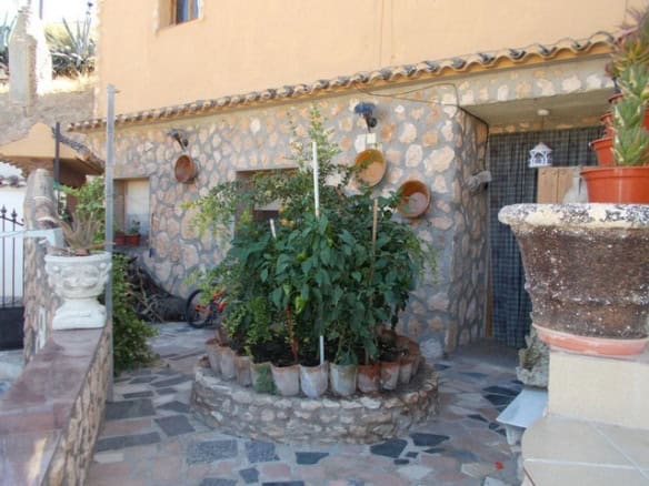 Town House in Cullar, Granada with lush garden and rustic stone exterior.