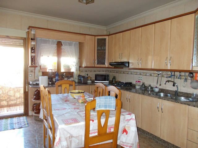 Charming town house kitchen in Cullar, Granada with wooden cabinets and dining area.