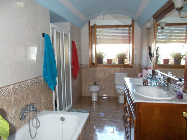 Charming town house bathroom with bathtub, bidet, and large window in Cullar, Granada.