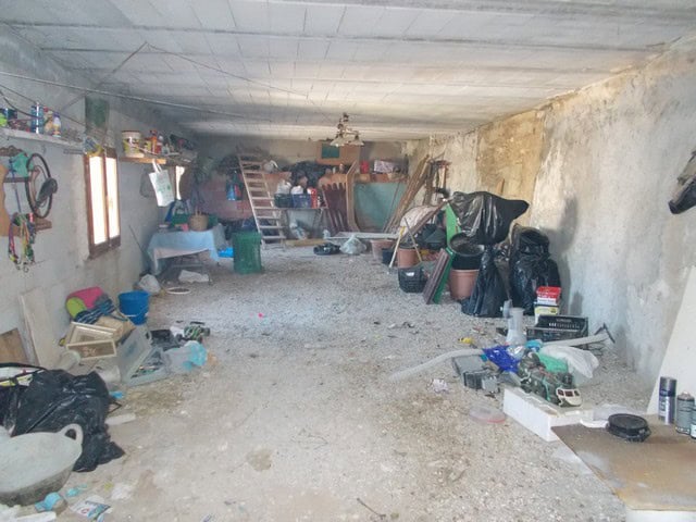 Spacious interior of a town house in Cullar, Granada, showcasing a cluttered garage or storage area.