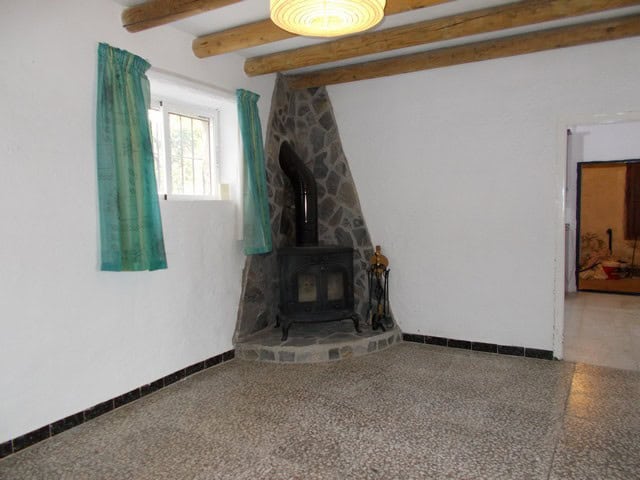 Cozy village home interior with stone fireplace and wooden ceiling beams in Cela, Almeria.