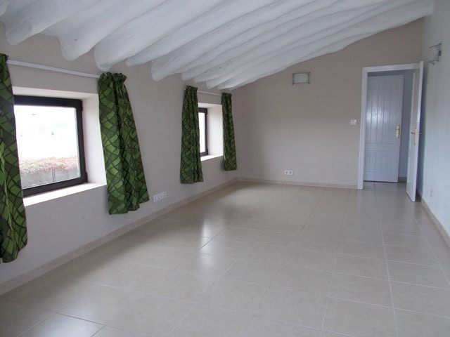 Spacious interior of a village property in Cela, Almeria, featuring white walls, green curtains, and.