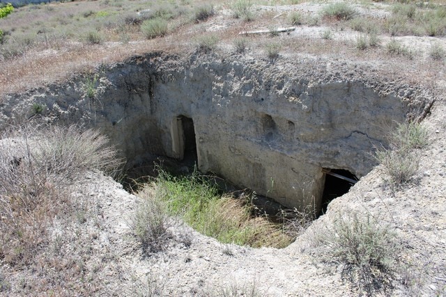 Cave house entrance in Caniles, Granada, surrounded by desert landscape.