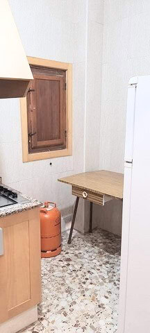 Kitchen with wooden cabinets and a small window in Zujar, Granada.
