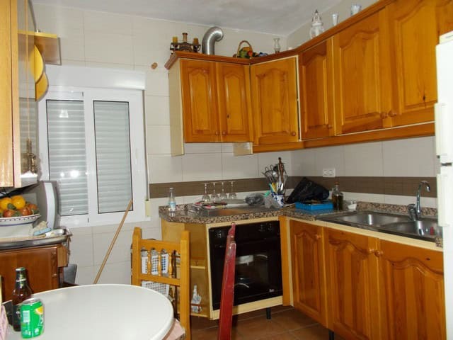 Charming kitchen of a cave house in Bacor, Granada, featuring wooden cabinets and modern appliances.