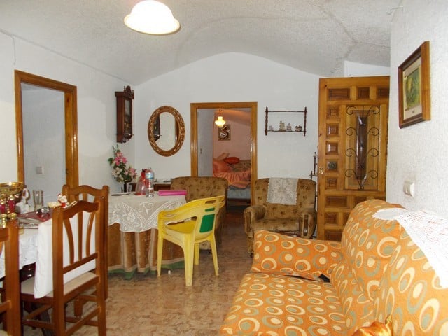 Charming interior of a cave house in Bacor, Granada, featuring rustic furniture and traditional deco.