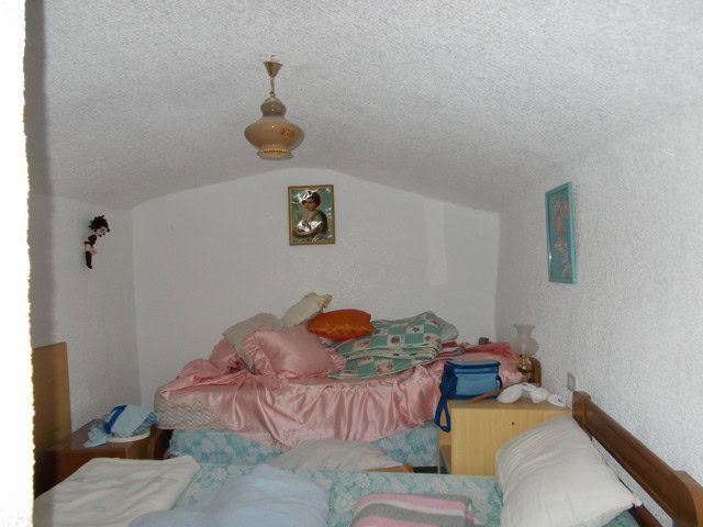 Cave house bedroom with cozy bed, colorful pillows, and rustic decor in Bacor, Granada. Unique livin.