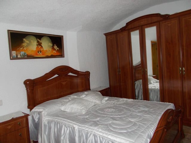 Charming bedroom featuring traditional wooden furniture in a unique cave house in Bacor, Granada. Pe.