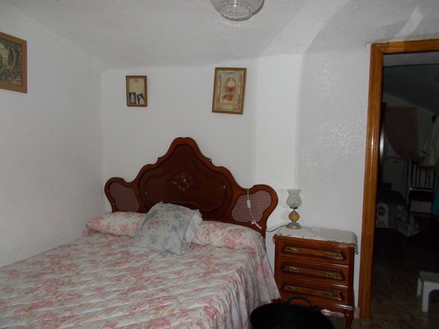 Charming cave house interior in Bacor, Granada, featuring a cozy bedroom with vintage furniture and.