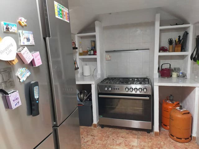 Cozy cave house kitchen with modern appliances in Benamaurel, Granada, featuring a stove, shelves, a.