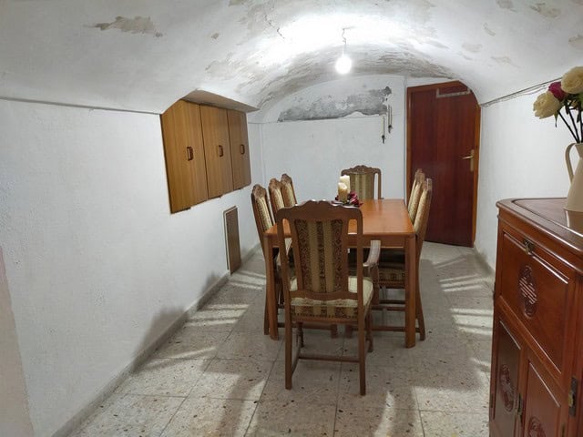 Charming cave house interior with a wooden dining table and six upholstered chairs in Benamaurel, Gr.