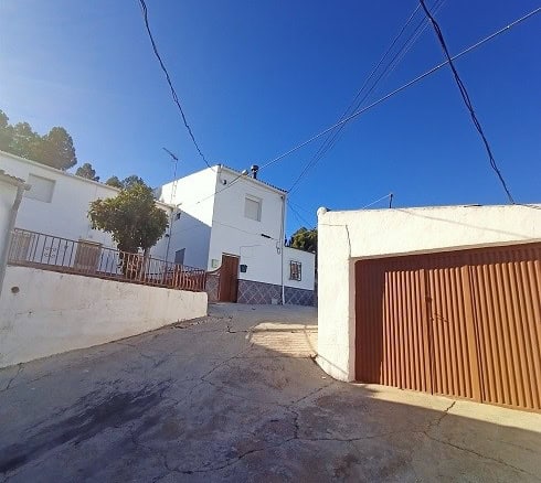 Village property with white exterior walls and a garage in Fontanar, Jaen.
