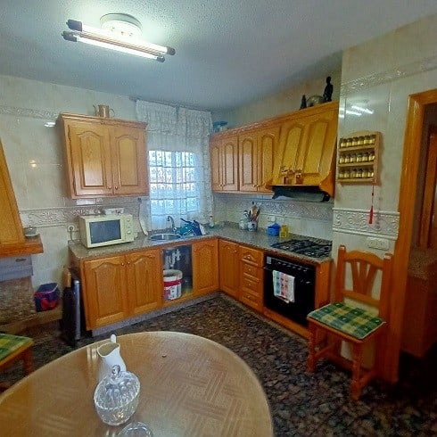 Kitchen with wooden cabinets and modern appliances in Fontanar, Jaen.