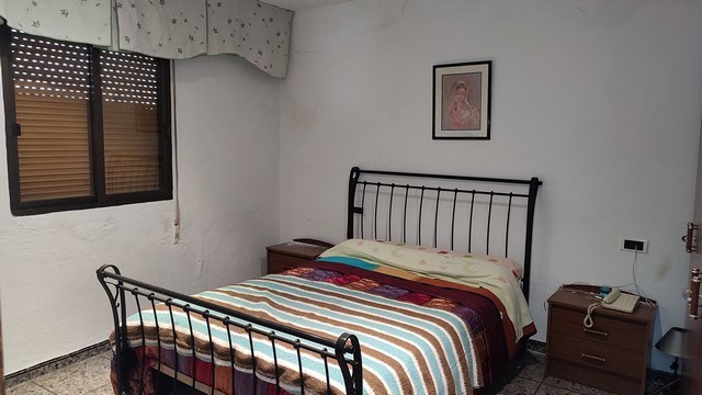 Cozy bedroom in a town house located in Caniles, Granada, featuring a metal bed frame and simple dec.