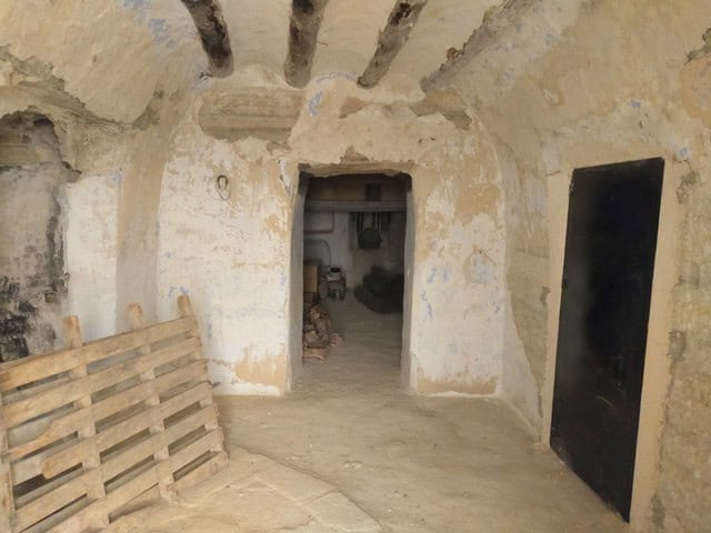 Cave house interior in Benamaurel, Granada, showcasing rustic stone walls and arched ceilings.