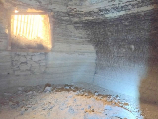 Cave house interior in Benamaurel, Granada with natural rock walls and small window.