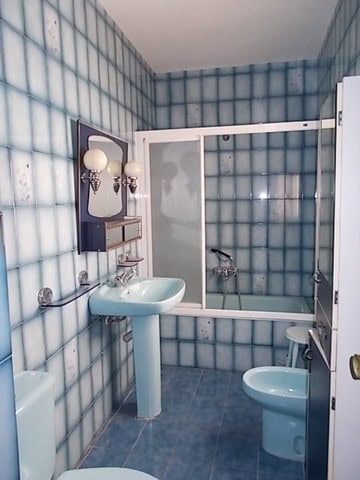 Charming village home bathroom in Somontin, Almeria with blue tiled walls, sink, toilet, and shower.