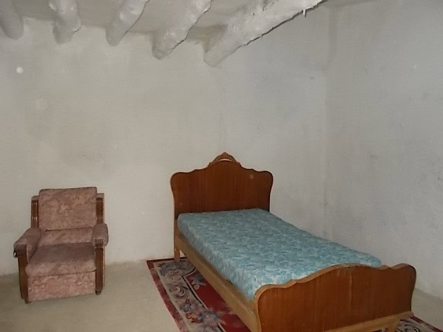 Charming rustic bedroom in Tijola, Almeria with vintage wooden bed and cozy armchair.