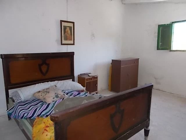 Charming bedroom in a rural property in Tijola, Almeria, featuring simple furnishings and a cozy atm.