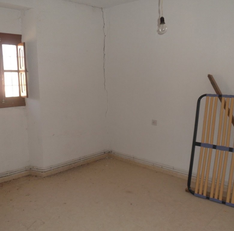 Interior of a village property in Campo Camara, Granada, showing a simple room with a window and min.