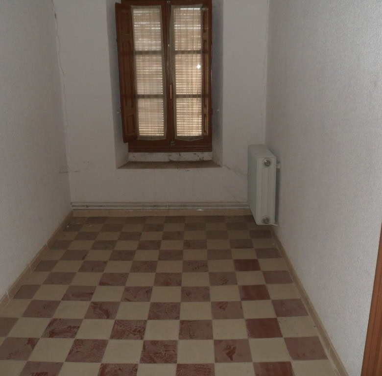 Interior view of a small village room with checkered floor and wooden window in Campo Camara, Granad.
