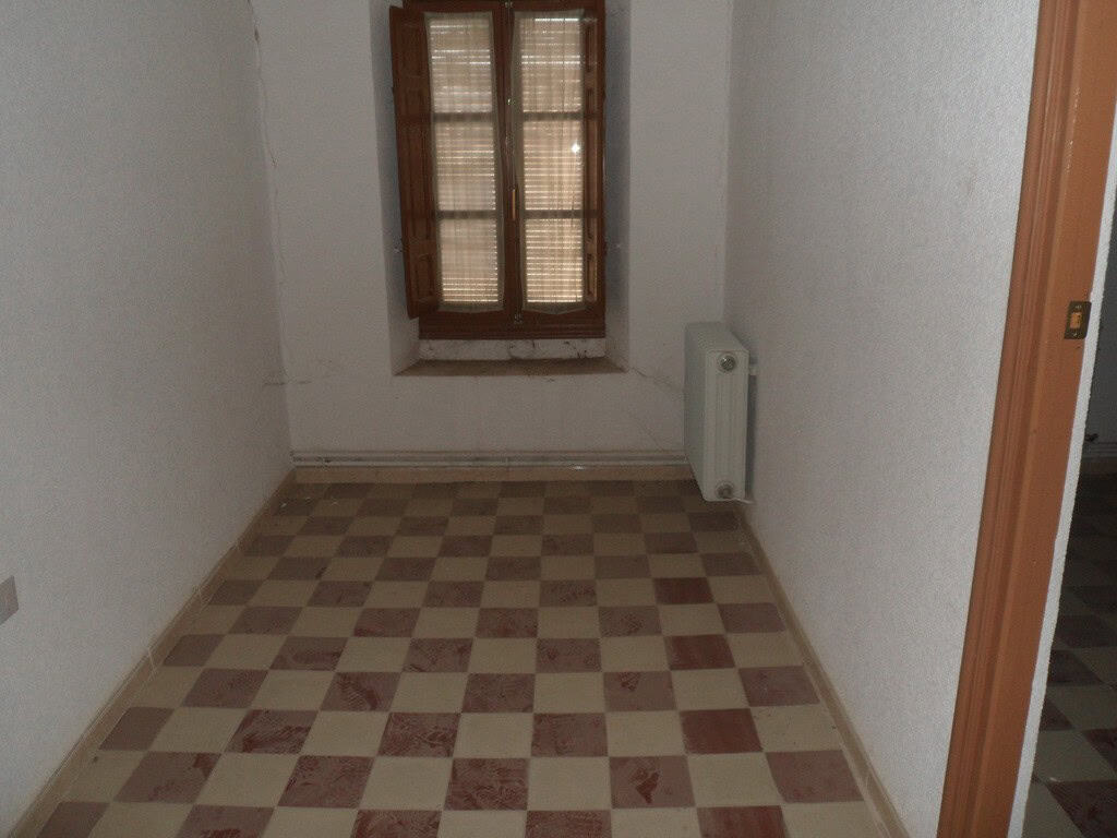 Interior view of a small village room with checkered floor and wooden window in Campo Camara, Granad.