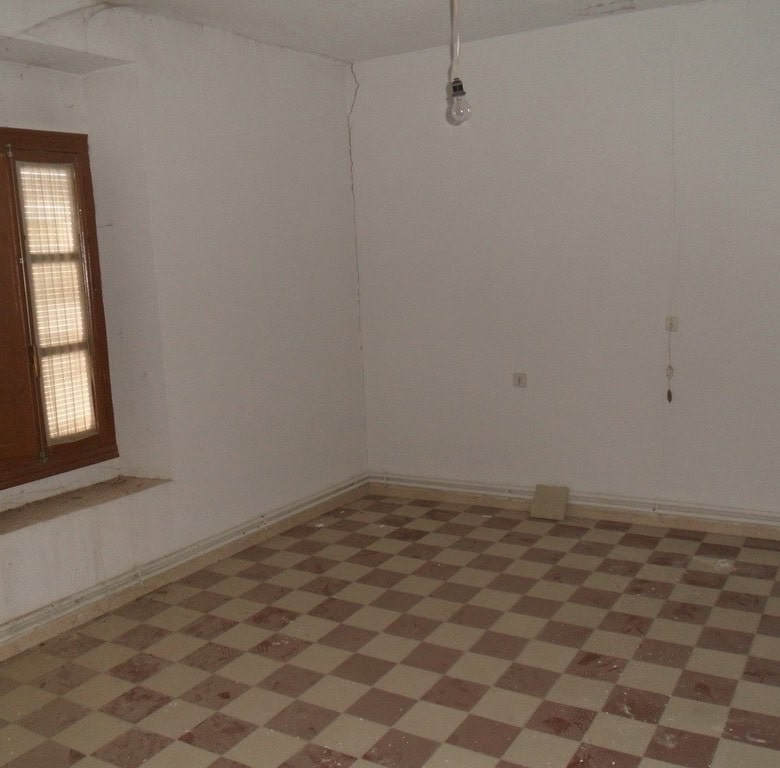 Interior view of a village property in Campo Camara, Granada, showing an empty room with a window an.