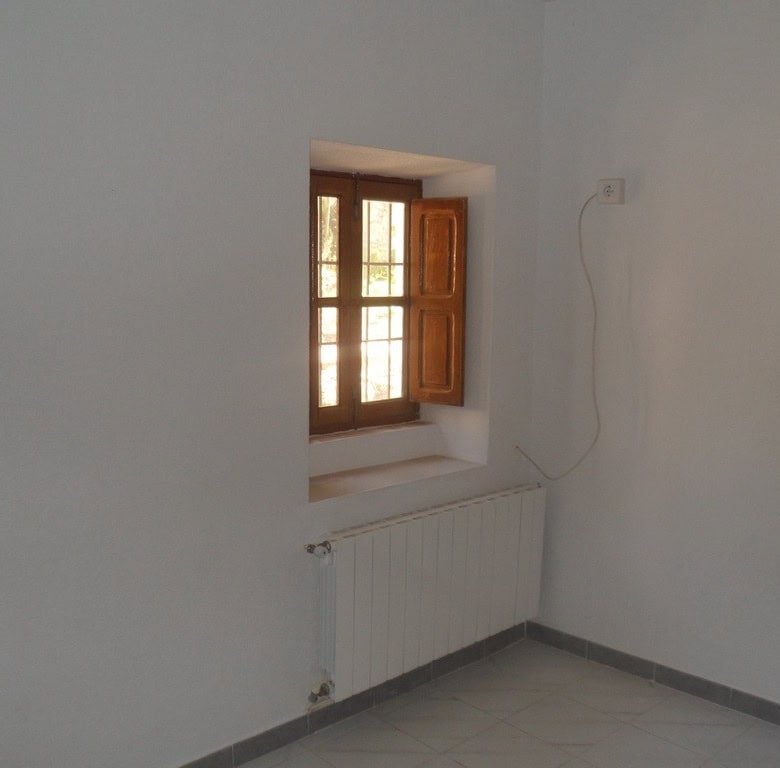 Cozy interior with wooden window in a rural village property in Campo Camara, Granada.
