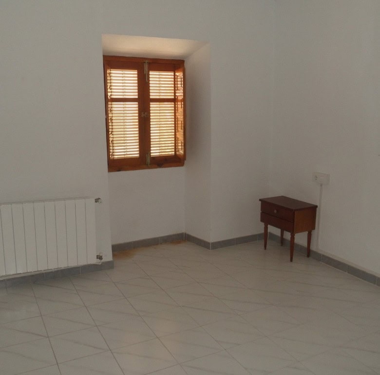 Interior of a simple village house in Campo Camara, Granada with a window, radiator, and small woode.