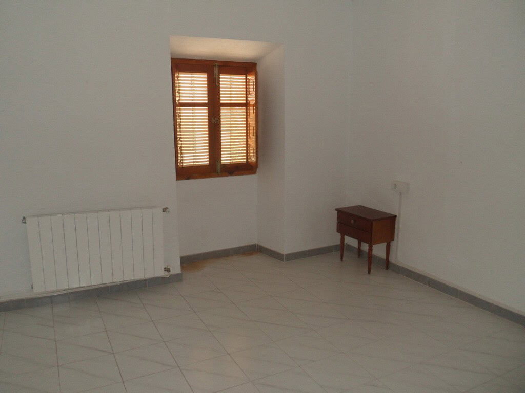 Interior of a simple village house in Campo Camara, Granada with a window, radiator, and small woode.
