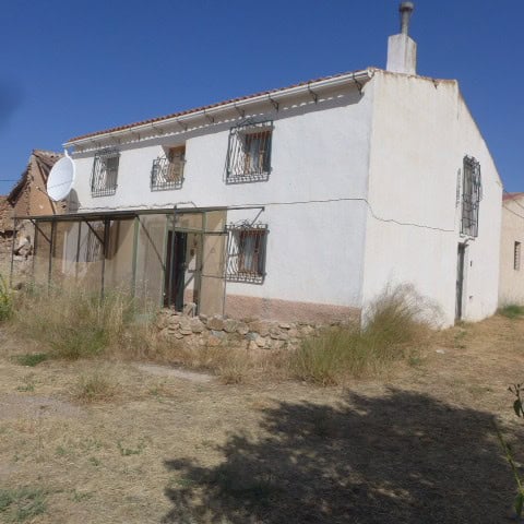 Chirivel rural property with white exterior walls, small windows, and a satellite dish, set in a sun.